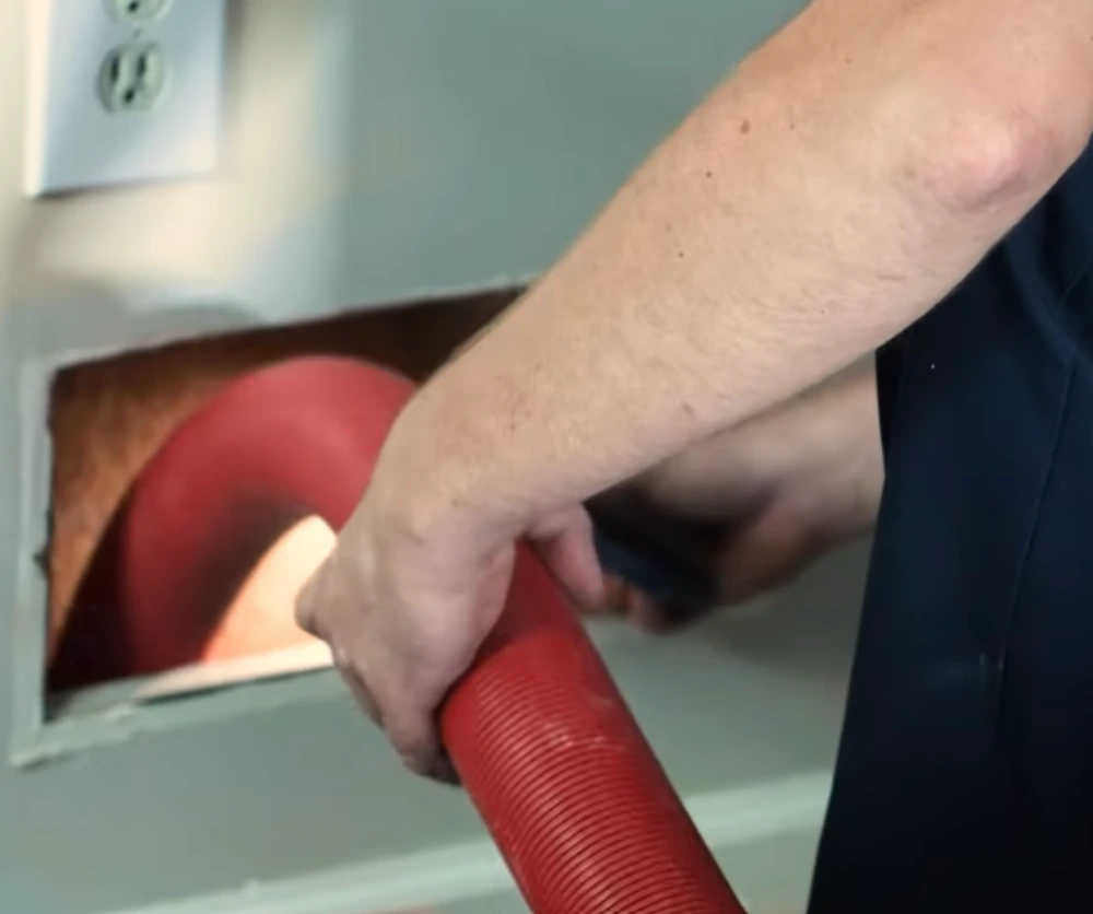 air duct cleaning pipe 1 A person inserting duct cleaning pipe in a vent