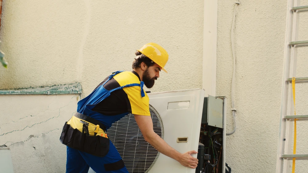 HVAC technician inspecting and cleaning an evaporator coil during an air duct service call